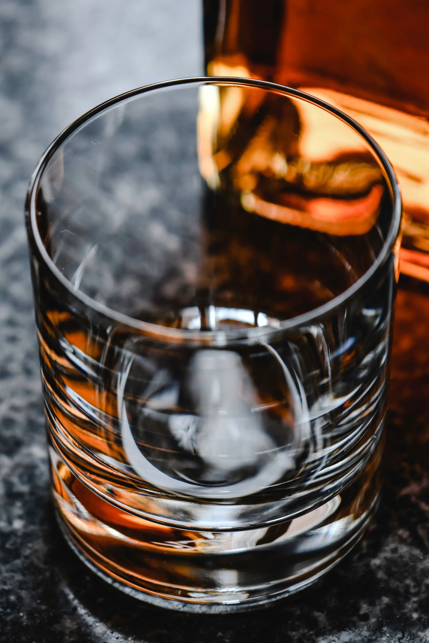 Glas whisky voor een fles op een donkere bar